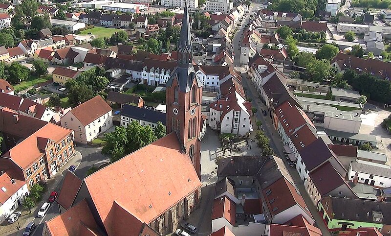 Hier sieht man eine Luftaufnahme von der Innenstadt Gräfenhainichens, im Vordergrund die Evangelische Stadtkirche, links das Paul-Gerhardt-Gymnasium und etwas weiter hinten den Oberen Stadtturm.