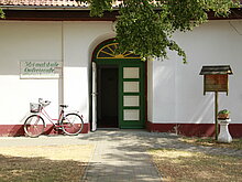 Geöffnete Eingangstür in das Galeriecafe. Links davor steht ein Fahrrad an der Häuserwand angelehnt