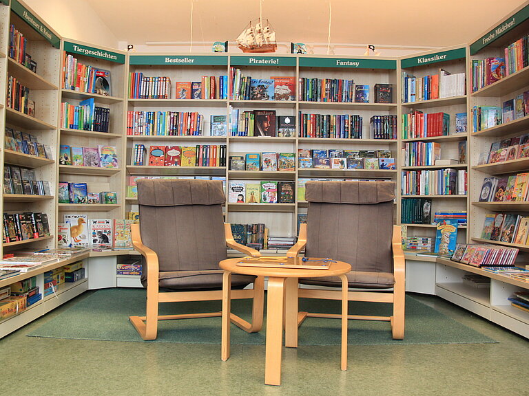 Bücherregale der Jugendecke mit zwei Schwingsesseln und kleinem Tisch..