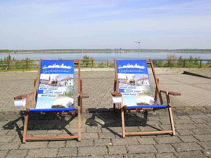 Zwei Liegestühle stehen auf der Betonfläche auf dem Stadtbalkon.