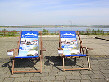 Zwei Liegestühle stehen auf der Betonfläche auf dem Stadtbalkon.